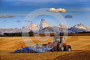Tractor Farming Ground Harvesting Crops in Fall Autumn Teton Mountains Rugged