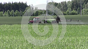 Tractor fertilize crop field at herbicides, pesticides. Panning