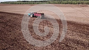 Tractor on the field makes organic fertilizers aerial survey with a drone