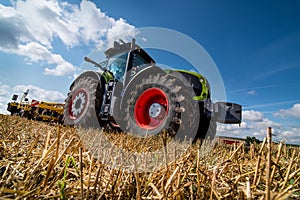 tractor in a field with stubble trailed equipment