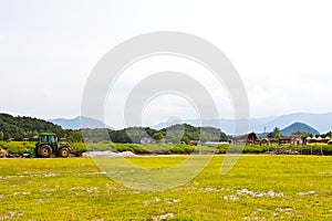 a tractor in a field in a wide field of mountains