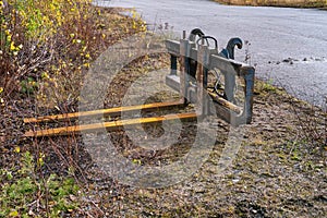 Tractor fork attachment stored on gravel ground at a side of asphalt road