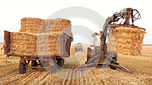 Tractor with fork grabber folding hay blocks.