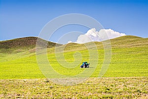 Tractor on green meadow with blue sky in Turkey, near Agri