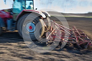 Tractor harrowing land in springtime photo