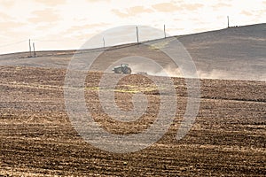 tractor harrowing the large brown field photo