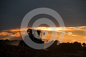 Tractor harrowing at sunset