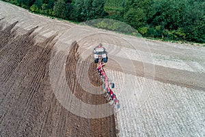 Tractor harrownig the large brown field