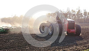 Tractor harvesting and soil cultivation for subsequent sowing. Field and dust in the sun, work in agriculture