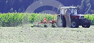 Tractor with hay tedder working on a mountain field