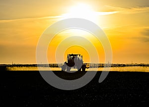 tractor with the help of a sprayer sprays liquid fertilizers on young wheat in the field