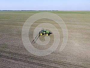 Tractor with hinged system of spraying pesticides. Fertilizing with a tractor, in the form of an aerosol, on the field of winter w