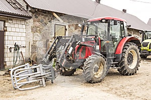 Tractor with hydraulic lift for carrying bales of hay and silage.