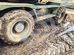 A tractor with large, black wheels in the mud. metal threshold with thick rubber wheels with tread. black wheel stuck in a puddle