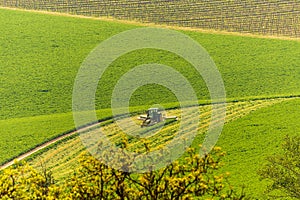 Tractor on a large green field with mowed lawn stripes. It is a sunny spring day in Czech Republic