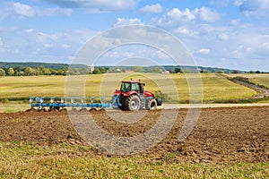 A tractor with a large plow plows a field. Tractor with agricultural attachment