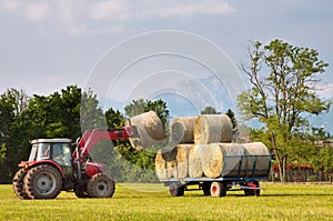 Tractor lifting hay bale on barrow