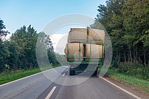 tractor loaded with several straw bales drives over a country road