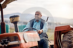 Tractor, man and driver on field for agriculture, countryside or sustainability in nature. Happy farmer worker driving