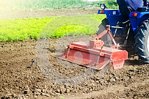 Tractor with milling machine loosens, grinds and mixes soil. Loosening the surface, cultivating the land for further planting.