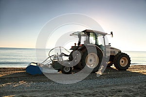 Tractor in morning takes garbage away on beach