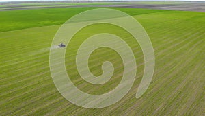 Tractor with mounted sprayer sprinkles herbicide and pesticide on crops field