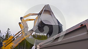 Tractor moves rubble to truck. Stock footage. Excavator-loader rakes rubble from pile at construction site and loads