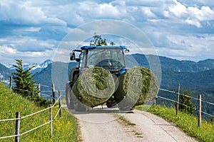 The tractor moving the bales of grass from the meadow