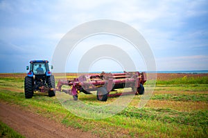 Tractor with mower in the field of sainfoin and alfalfa