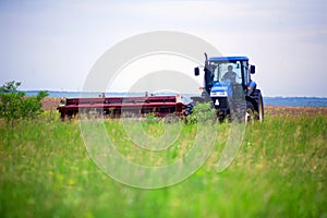 Tractor with mower in the field of sainfoin and alfalfa