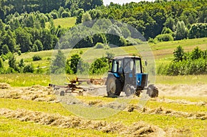 tractor with mower to mow grass in meadows . Tractor cut hay from alfalfa. Preparation of animal feed for rabbits, cows