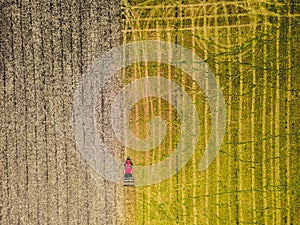 Tractor mowing agricultural field. Aerial view. Cultivating field.