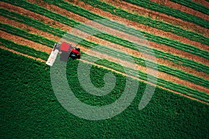 Tractor mowing green field, aerial view