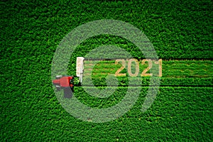 Tractor mowing green field, and happy new year 2021