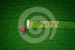 Tractor mowing green field. New year 2022 concept of agriculture and farming