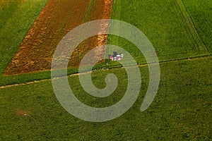 Tractor mowing pasture on big field of neatly cultivated land
