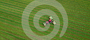 Tractor mows the grass on a green field aerial view