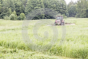 Tractor mows the grass. harvesting hay for the winter