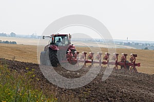 Tractor with plow on arable land processes