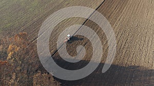 Tractor plowing agricultural soil, drone aerial view