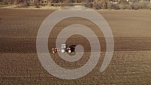 Tractor plowing agricultural soil, drone aerial view