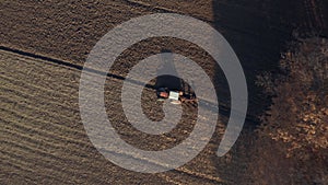 Tractor plowing agricultural soil, drone aerial view