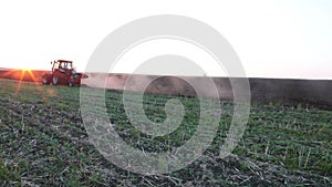 Tractor plowing the black earth plow field at sunset