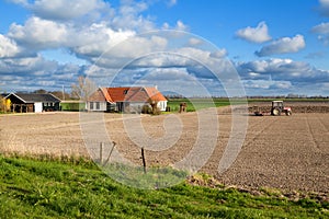 Tractor plowing field by farmhouse