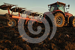 Tractor plowing field the land at sunset
