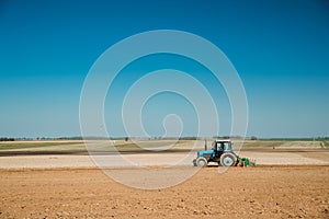 Tractor Plowing Field In Spring Season. Beginning Of Agricultural Spring Season. Cultivator Pulled By A Tractor In