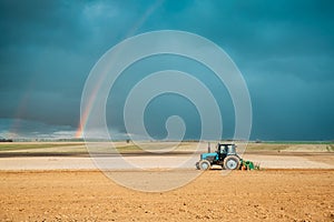 Tractor Plowing Field In Spring Season. Beginning Of Agricultural Spring Season. Cultivator Pulled By A Tractor In