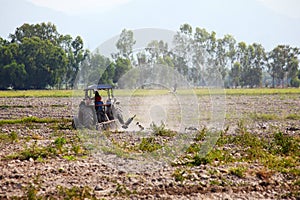 Tractor plowing field in sunny day