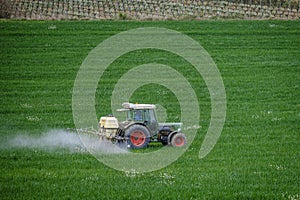 A tractor plowing an intense green crop field