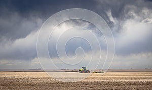 Tractor plowing a wheat field under a dramatic sky